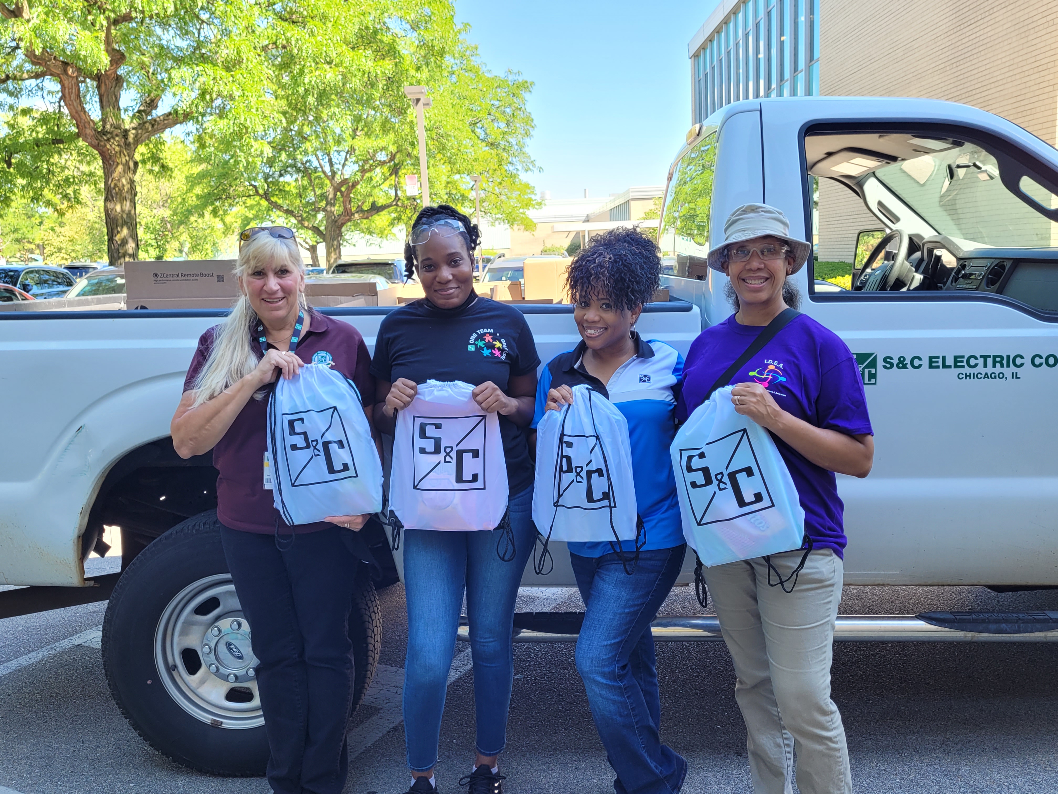 Four team members pose with donations for a local school